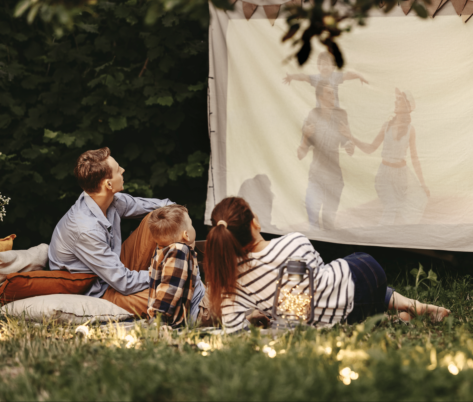 Image of family watching movie outdoors together in backyard.