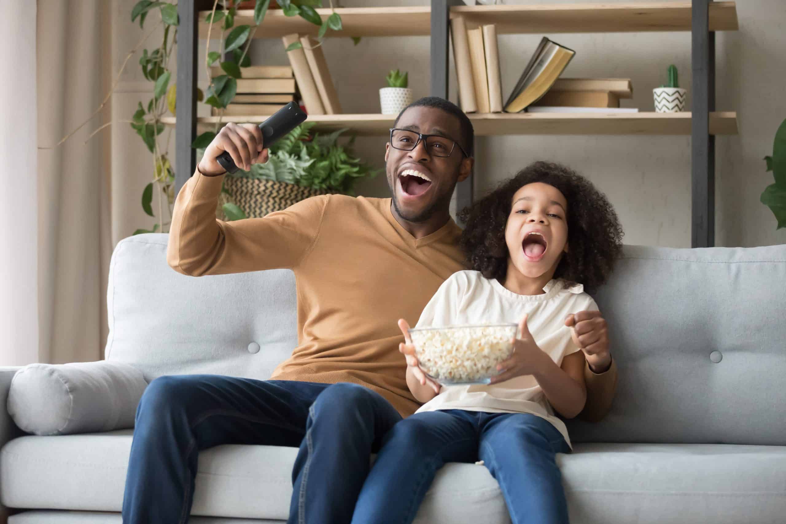 Picture of happy father watching TV with his daughter.
